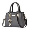 Gray handbag with decorative strap and embellishments on a white background
