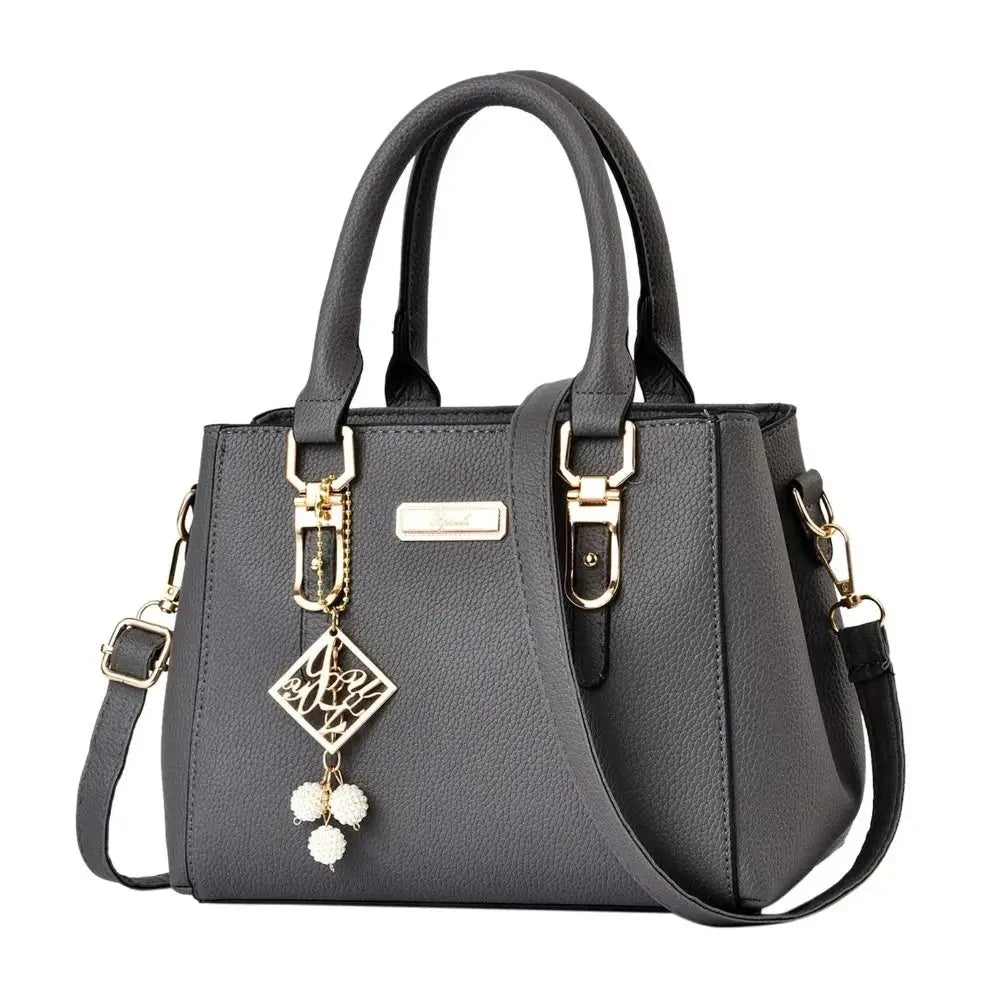 Gray handbag with decorative strap and embellishments on a white background