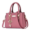 Pink handbag with gold accents and a decorative charm on a white background