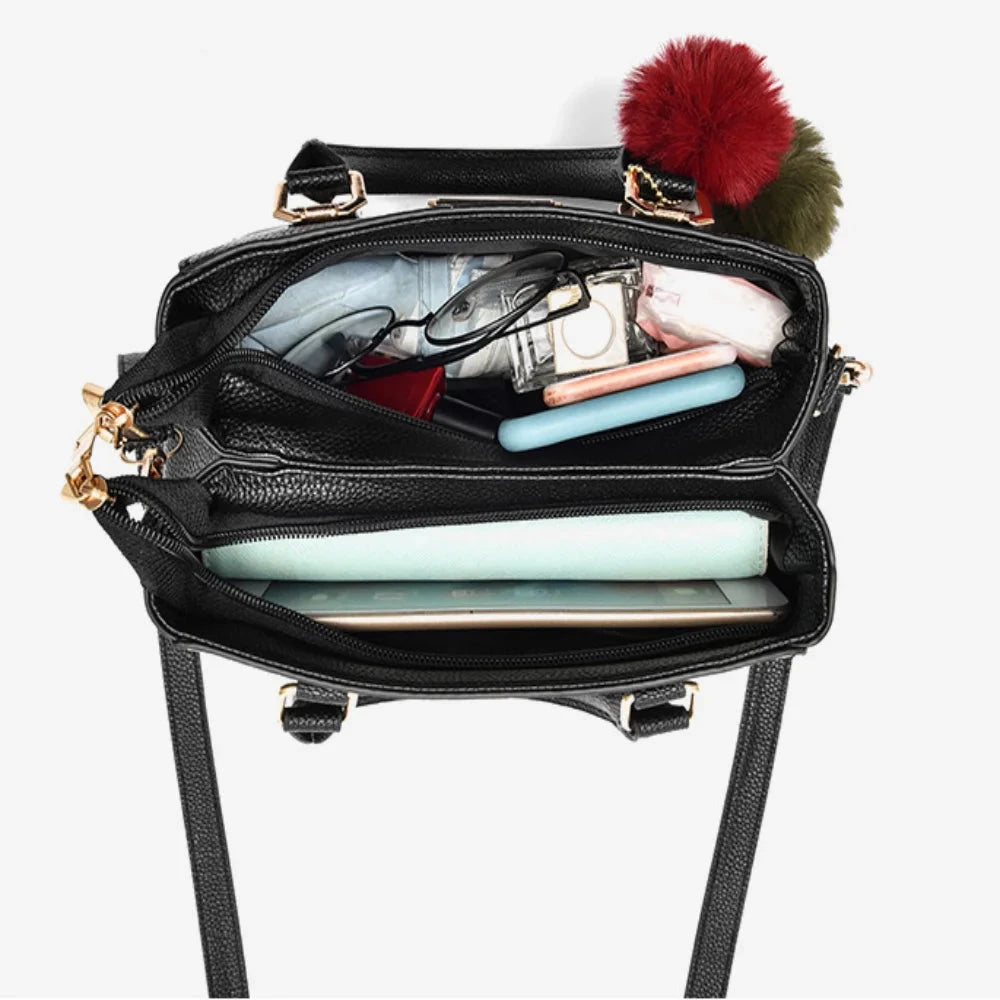Black handbag with colorful pom-poms on a white background