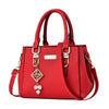 Red handbag with gold accents and a decorative charm on a white background