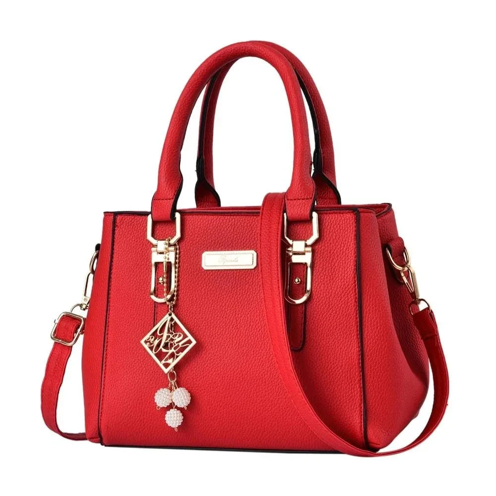 Red handbag with gold accents and a decorative charm on a white background