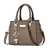 Brown handbag with decorative strap and pendant on a white background