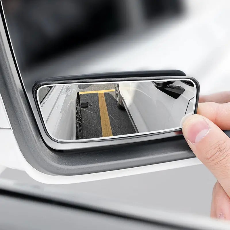 Car window mirror attached to a car window with a hand holding it