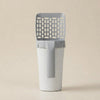 A modern gray and white plastic litter box scoop with a slotted top, shown on a solid beige background.