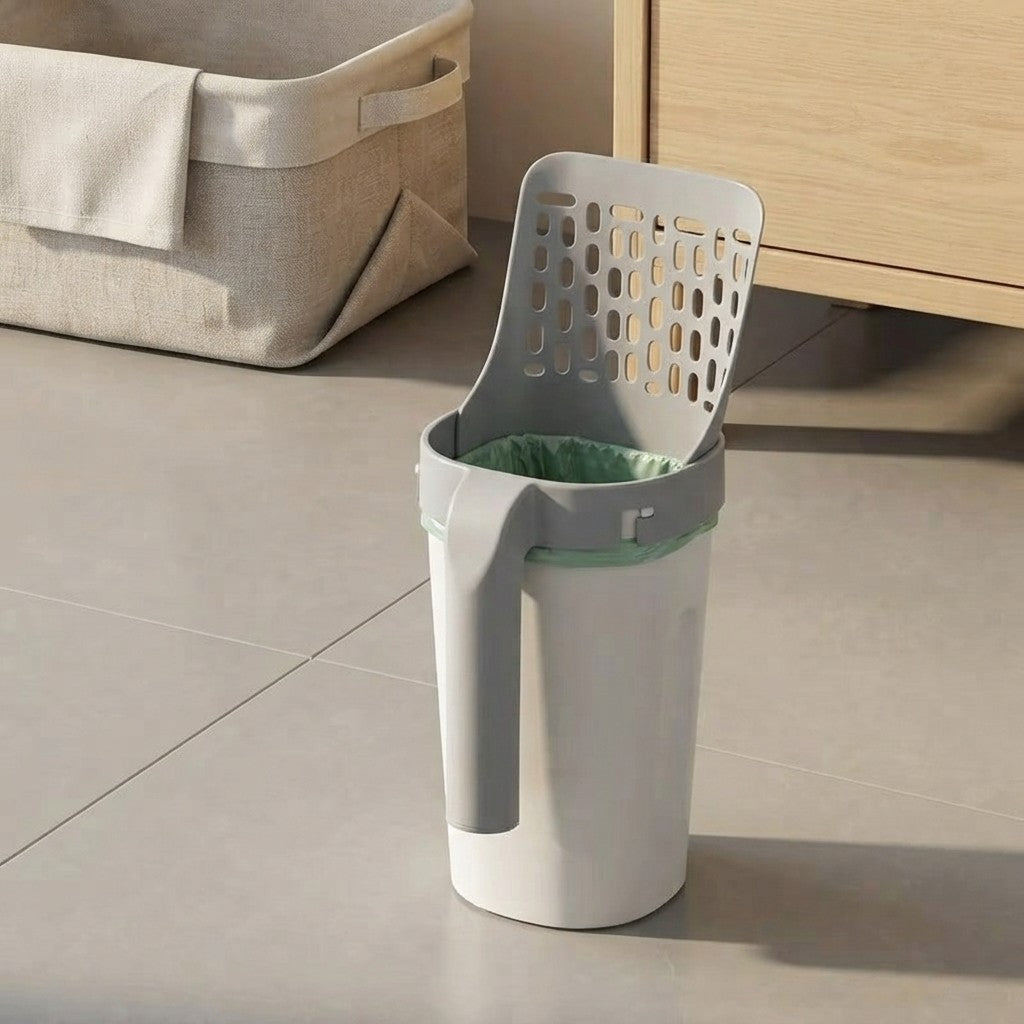 A white and gray automatic sifting trash can with a green-lined inner bin, shown on a tiled floor next to a wooden cabinet.