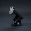 A black plastic suction cup phone mount with an adjustable arm and a mounting clip, shown on a dark gray studio background