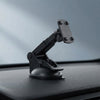 A black adjustable suction cup car mount with a phone holder clip, shown attached to a car dashboard against a blurred blue-gray background.