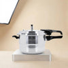 A stainless steel 22-inch pressure cooker with black handles, displayed on a metallic stand against a warm beige background.