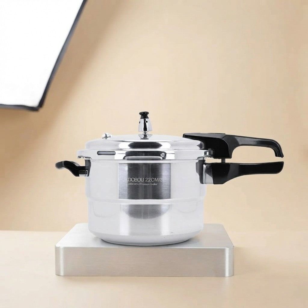 A stainless steel 22-inch pressure cooker with black handles, displayed on a metallic stand against a warm beige background.